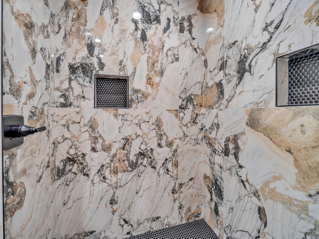 interior details featuring a marble finish shower