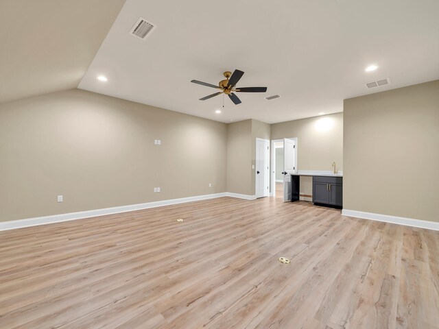 unfurnished living room with vaulted ceiling, light wood-type flooring, sink, and ceiling fan