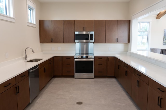 kitchen featuring light countertops, appliances with stainless steel finishes, a sink, and a wealth of natural light