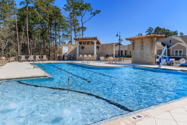 pool with fence, a pergola, and a patio