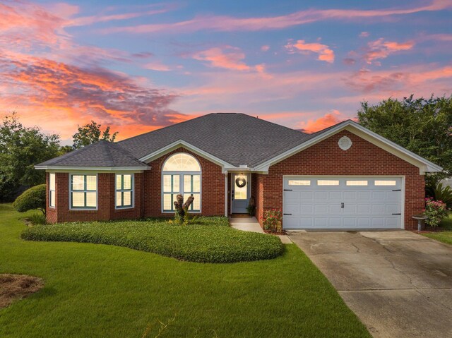 ranch-style house with a garage and a yard