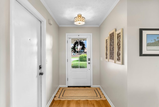 doorway with a textured ceiling, hardwood / wood-style flooring, and ornamental molding