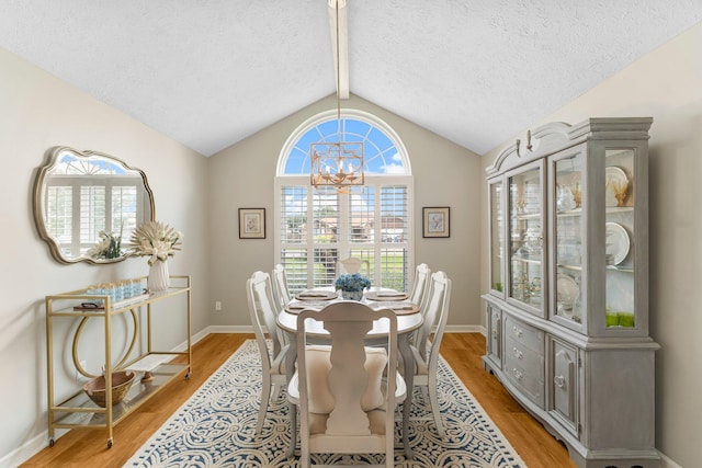 dining area with hardwood / wood-style flooring, vaulted ceiling with beams, a chandelier, and a textured ceiling