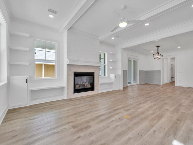 unfurnished living room featuring ceiling fan, light wood-type flooring, ornamental molding, beam ceiling, and a tiled fireplace