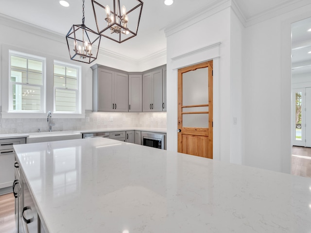 kitchen featuring light stone counters, pendant lighting, light hardwood / wood-style flooring, and ornamental molding