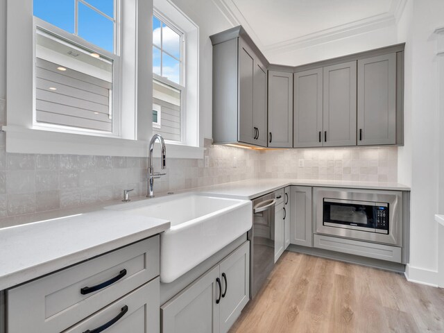 kitchen featuring ornamental molding, light hardwood / wood-style flooring, stainless steel appliances, and backsplash