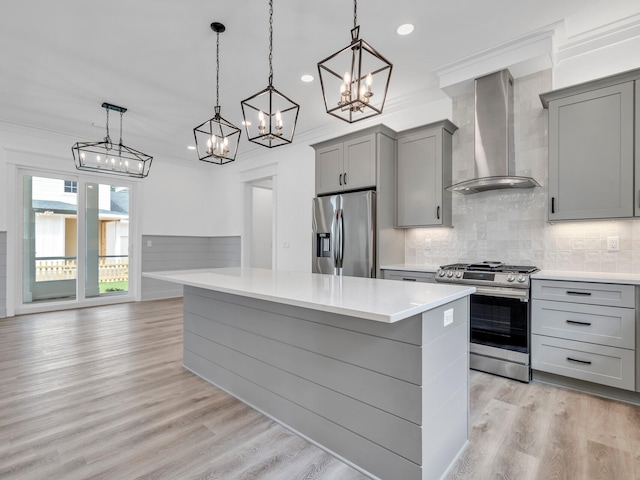 kitchen featuring light hardwood / wood-style floors, appliances with stainless steel finishes, decorative backsplash, and wall chimney exhaust hood