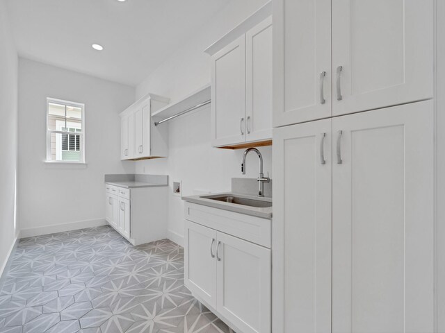 laundry area with washer hookup, light tile patterned floors, cabinets, and sink