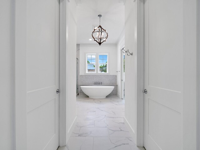 hall featuring a notable chandelier, crown molding, and light tile patterned floors