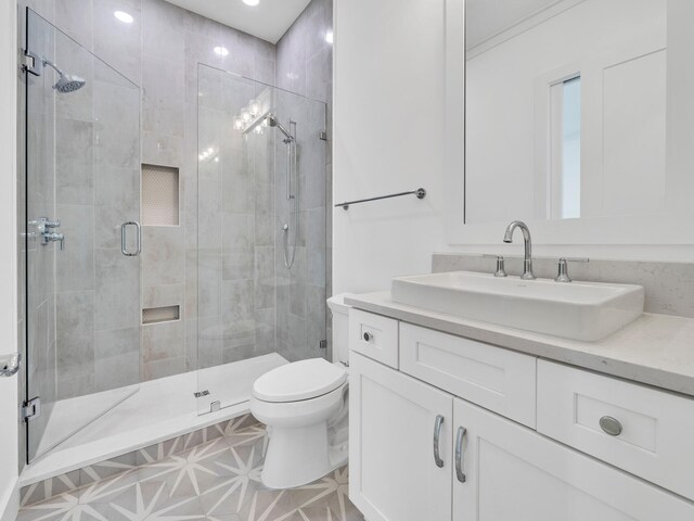 bathroom with tile patterned flooring, a shower with door, toilet, and vanity