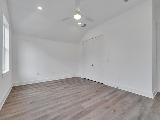 empty room with plenty of natural light, hardwood / wood-style flooring, vaulted ceiling, and ceiling fan