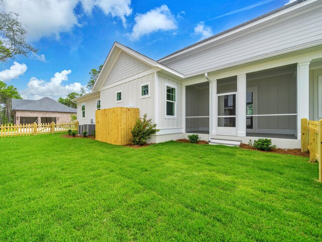 rear view of house with a sunroom and a yard