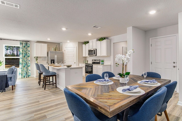 dining space with a textured ceiling and light hardwood / wood-style floors