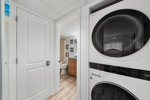 washroom featuring stacked washer and clothes dryer and light wood-type flooring