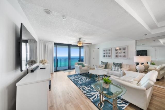 living room featuring a water view, a wealth of natural light, ceiling fan, and light wood-type flooring