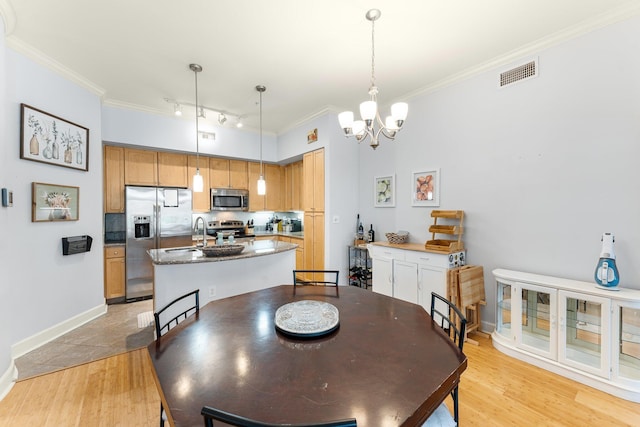 dining area featuring crown molding, light hardwood / wood-style floors, track lighting, and a notable chandelier