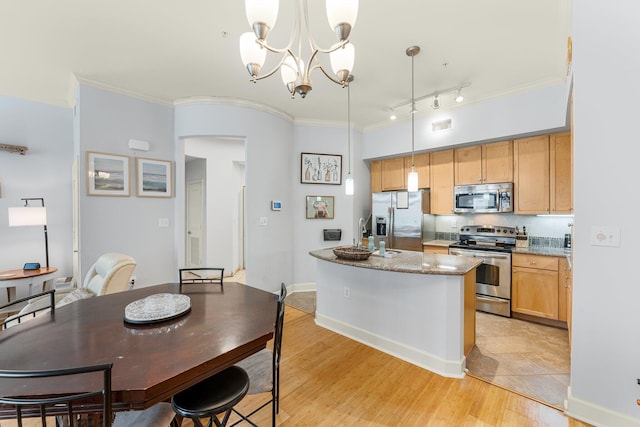 kitchen featuring an inviting chandelier, a center island with sink, light stone countertops, appliances with stainless steel finishes, and decorative light fixtures