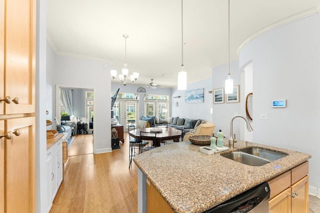 kitchen with french doors, ornamental molding, ceiling fan with notable chandelier, a kitchen island with sink, and sink