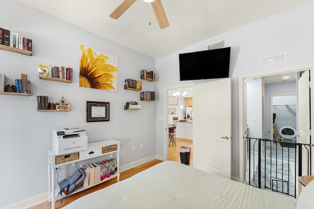 bedroom with light wood-type flooring, ceiling fan with notable chandelier, and lofted ceiling