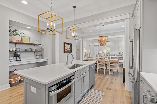 kitchen featuring sink, an island with sink, hanging light fixtures, and appliances with stainless steel finishes