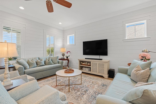 living room featuring hardwood / wood-style flooring, ceiling fan, and wooden walls