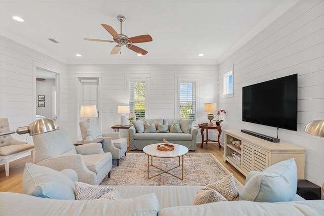 living room with ceiling fan, light hardwood / wood-style floors, and wood walls