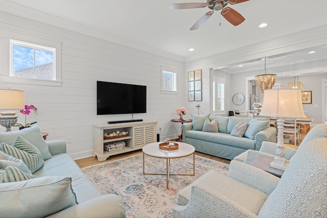 living room featuring ceiling fan with notable chandelier, hardwood / wood-style flooring, plenty of natural light, and wooden walls