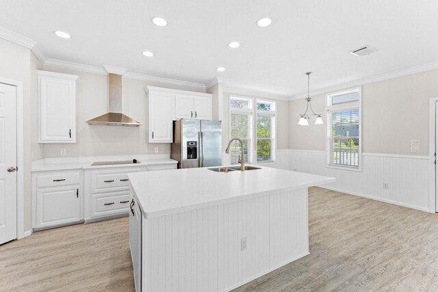 kitchen featuring sink, white cabinets, a kitchen island with sink, stainless steel fridge with ice dispenser, and wall chimney exhaust hood