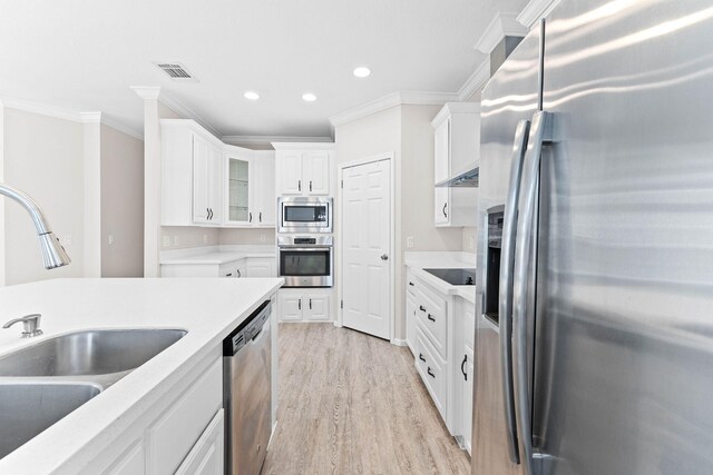 kitchen with white cabinetry, ornamental molding, appliances with stainless steel finishes, and sink