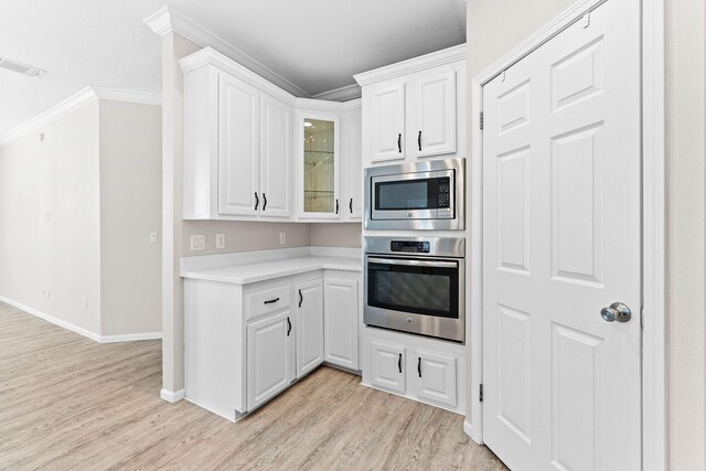 kitchen featuring crown molding, light hardwood / wood-style flooring, white cabinets, and appliances with stainless steel finishes