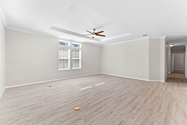 empty room featuring crown molding, ceiling fan, a raised ceiling, and light hardwood / wood-style flooring