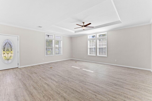 interior space with ceiling fan, ornamental molding, a raised ceiling, and light hardwood / wood-style floors