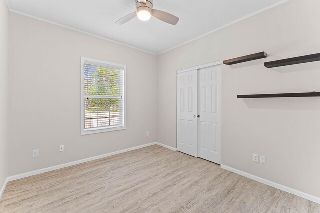 unfurnished bedroom featuring ornamental molding, light hardwood / wood-style flooring, ceiling fan, and a closet