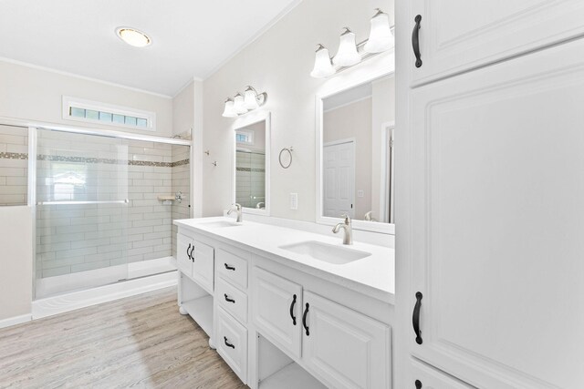 bathroom featuring a shower with door, vanity, wood-type flooring, and ornamental molding