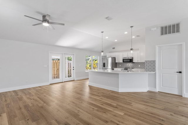 kitchen with white cabinetry, hanging light fixtures, backsplash, high quality fridge, and vaulted ceiling