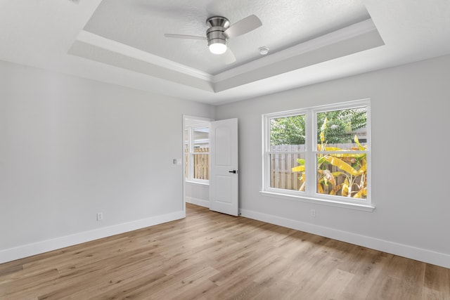 unfurnished room with a raised ceiling, ceiling fan, a textured ceiling, and light hardwood / wood-style flooring