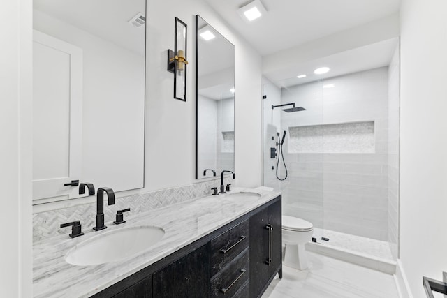 bathroom with tile patterned floors, tiled shower, toilet, and double sink vanity