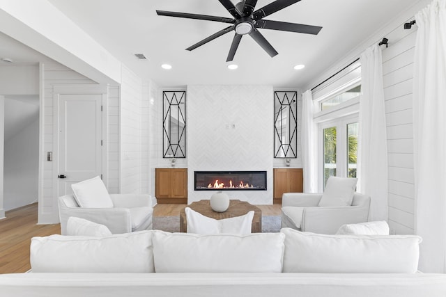 living room with light hardwood / wood-style floors, a fireplace, and ceiling fan