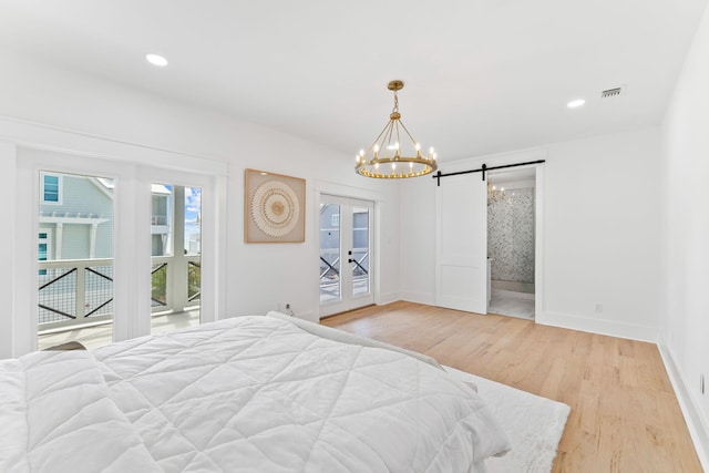 bedroom with a notable chandelier, french doors, access to exterior, a barn door, and light hardwood / wood-style floors