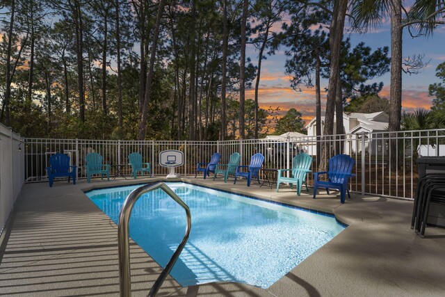 pool at dusk with a patio area