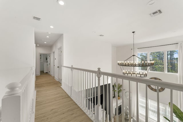 hall featuring light hardwood / wood-style flooring and a notable chandelier