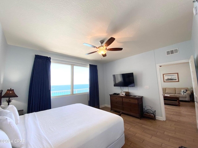 bedroom with a textured ceiling, hardwood / wood-style flooring, and ceiling fan