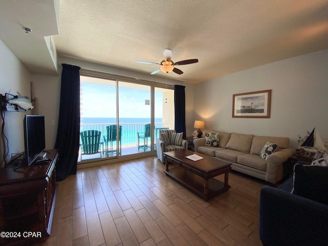 living room with hardwood / wood-style floors, ceiling fan, and a textured ceiling