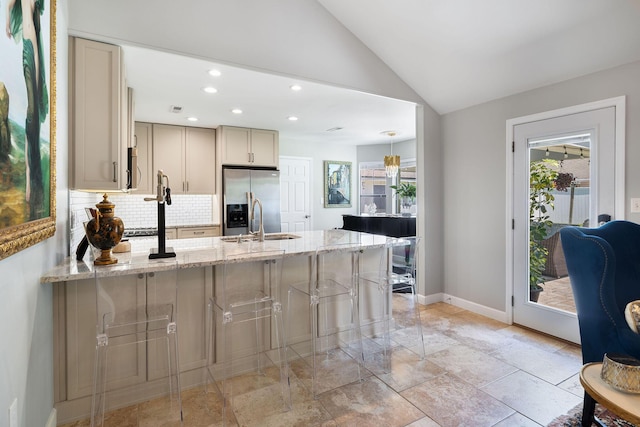 kitchen with stainless steel refrigerator with ice dispenser, sink, light stone counters, vaulted ceiling, and backsplash