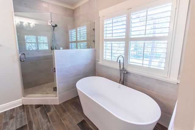 bathroom featuring tile walls, plenty of natural light, plus walk in shower, and hardwood / wood-style floors