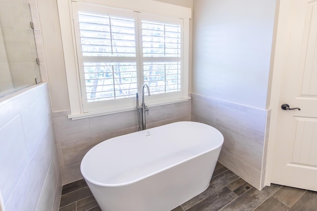 bathroom featuring a freestanding bath, wainscoting, tile walls, and wood tiled floor