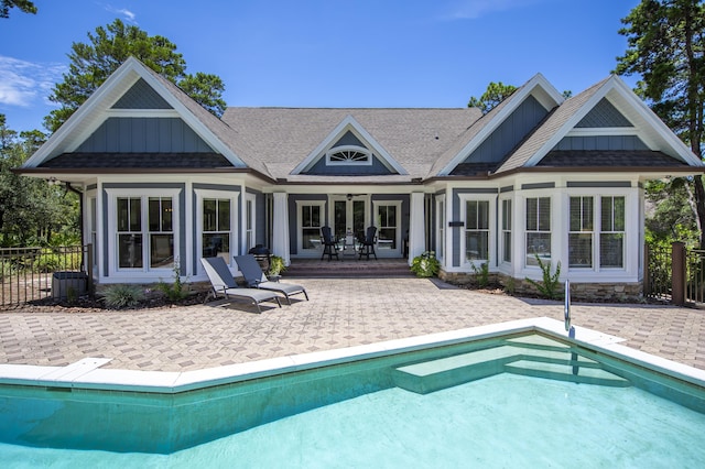 rear view of house featuring board and batten siding, a patio area, and an outdoor pool