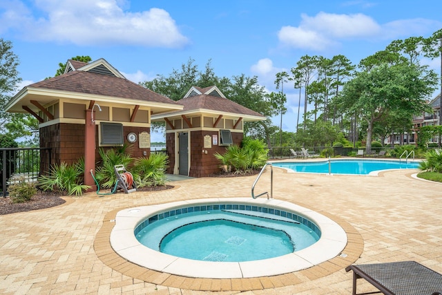 view of swimming pool featuring a hot tub and a patio area