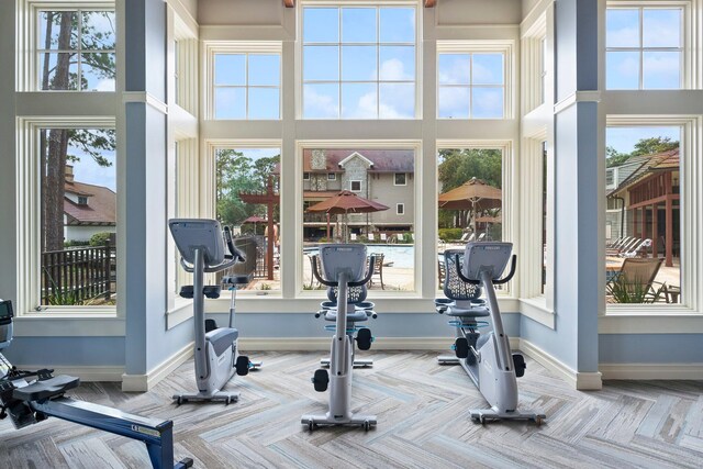 workout room featuring a towering ceiling, plenty of natural light, and light parquet floors