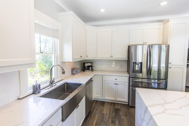 kitchen with backsplash, white cabinetry, stainless steel appliances, and light stone counters